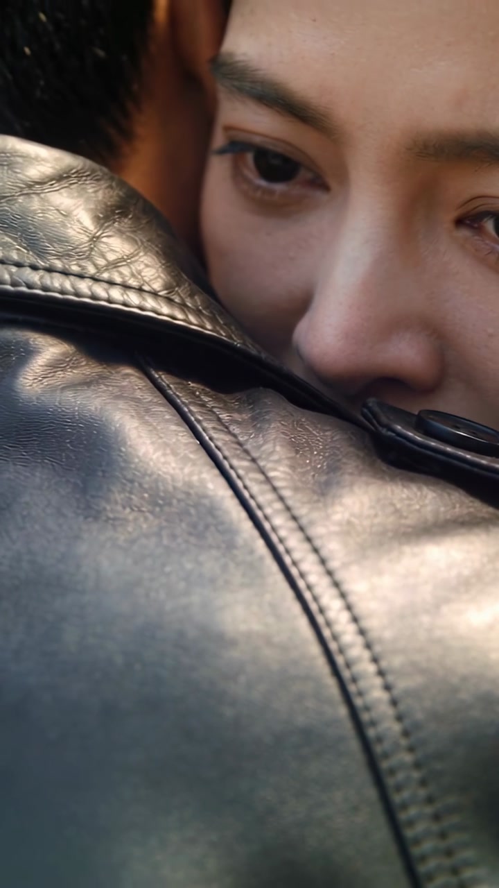 Vertical video: Embracing partner, woman pressing into leather jacket closeup, briefly closing eyes