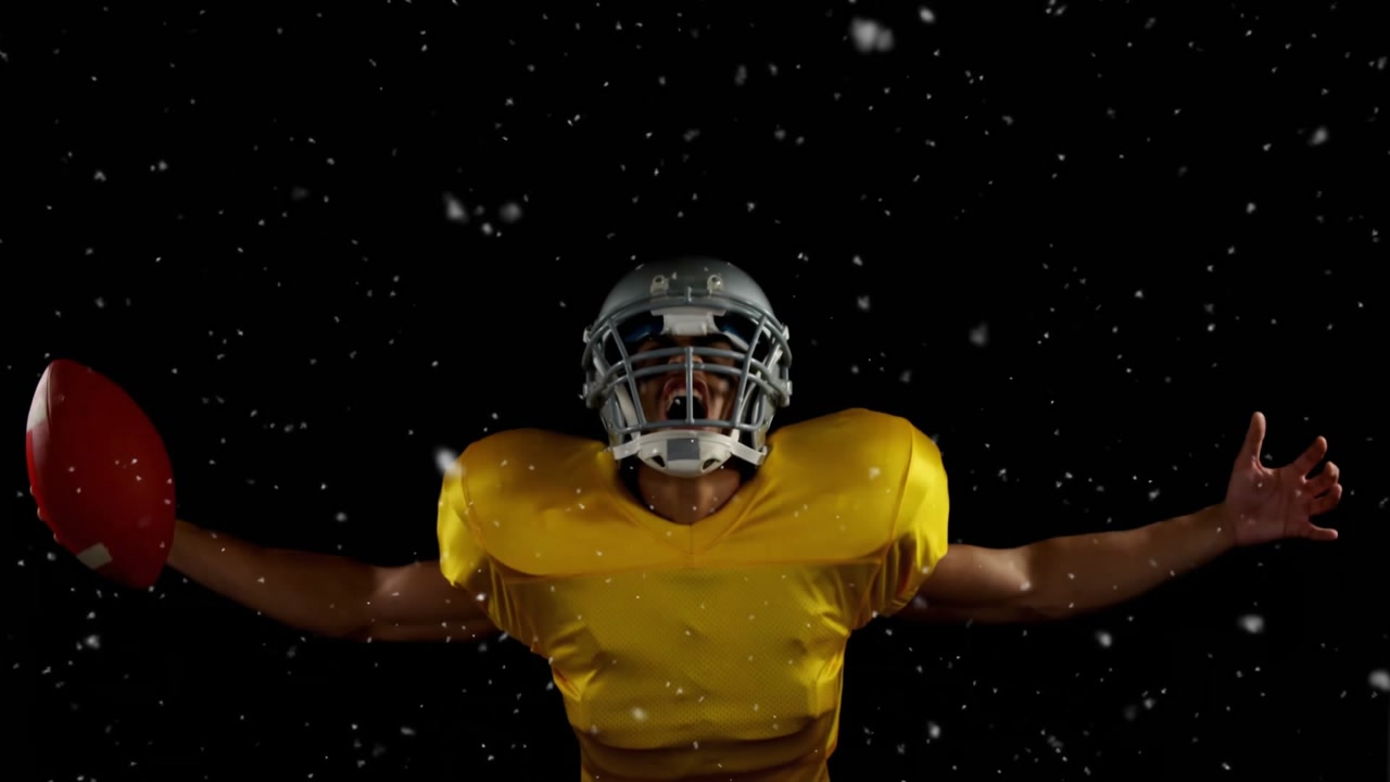 Football player raising arms celebrating holding football as particles drifting revealing helmet