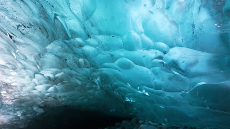 panning shot blue colored ice cave glacier and lighting sun behind the icy wall - visiting nature of iceland