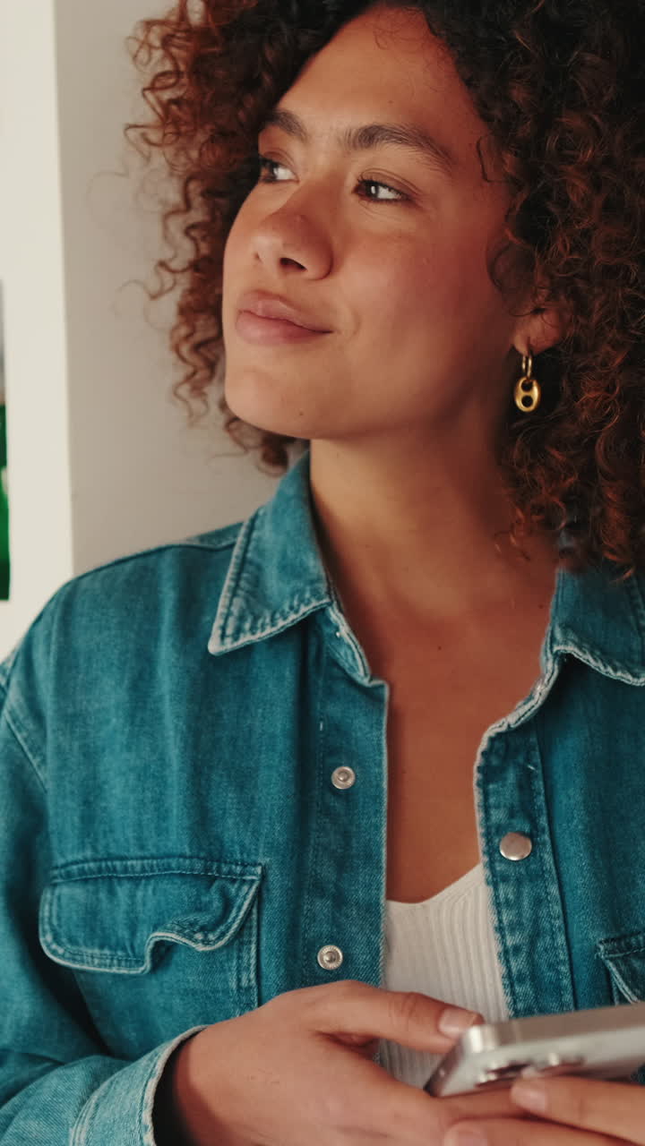Young Woman with Curly Hair Looks Up from Smartphone