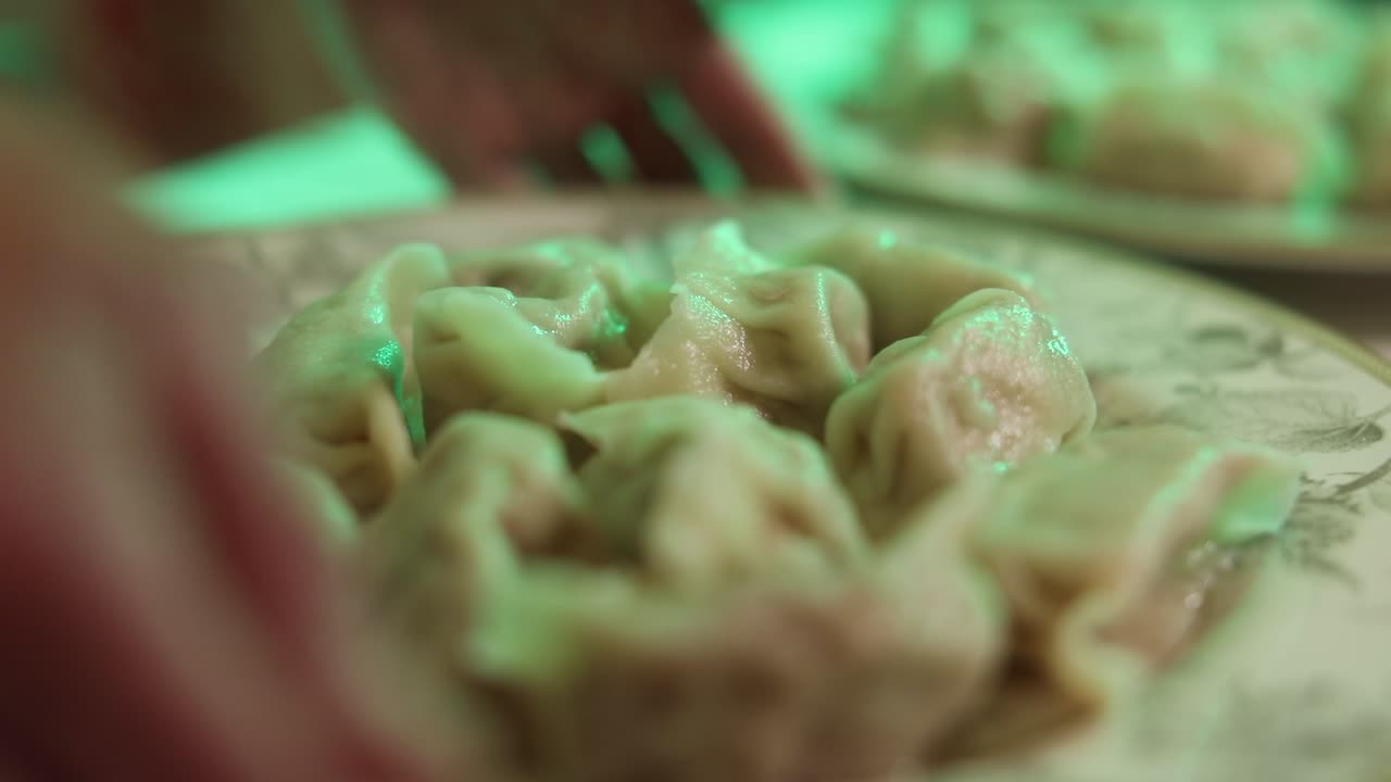 Close up shot of two plates of freshly boiled dumplings, chef sets the plate down