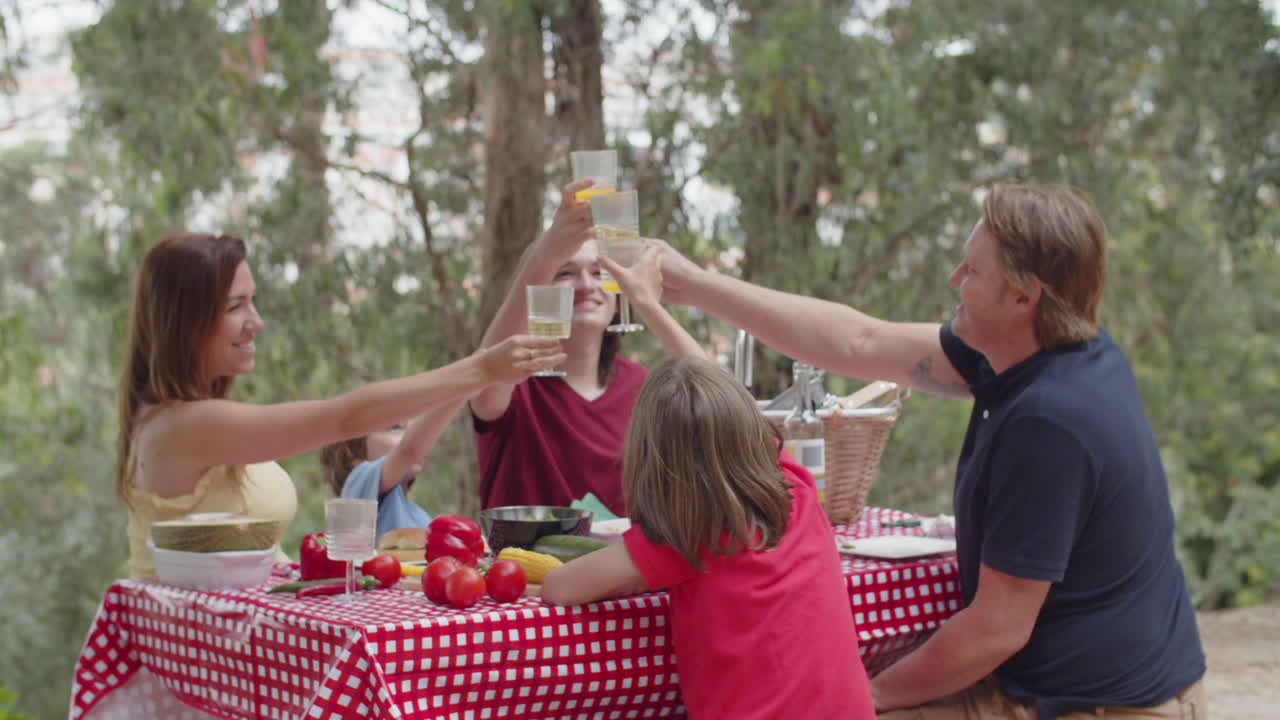 posibilidad remota de una familia feliz sentada a la mesa y tintineando vasos durante un picnic en el bosque