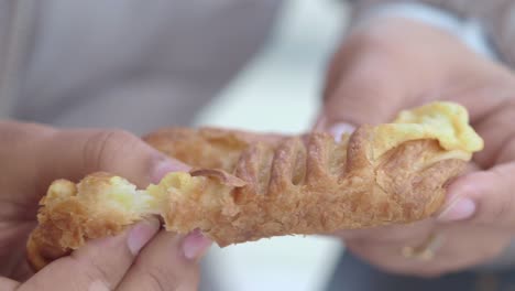 hands holding and eating a pastry