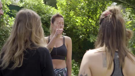 Yoga-trainer-talking-with-group-in-park