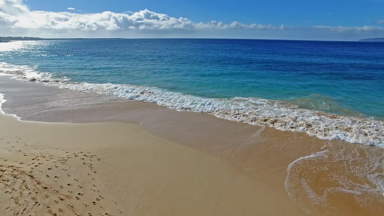 Ripresa panoramica di Maui, Hawaii, con spiaggia sabbiosa, onde e splendide acque blu.
