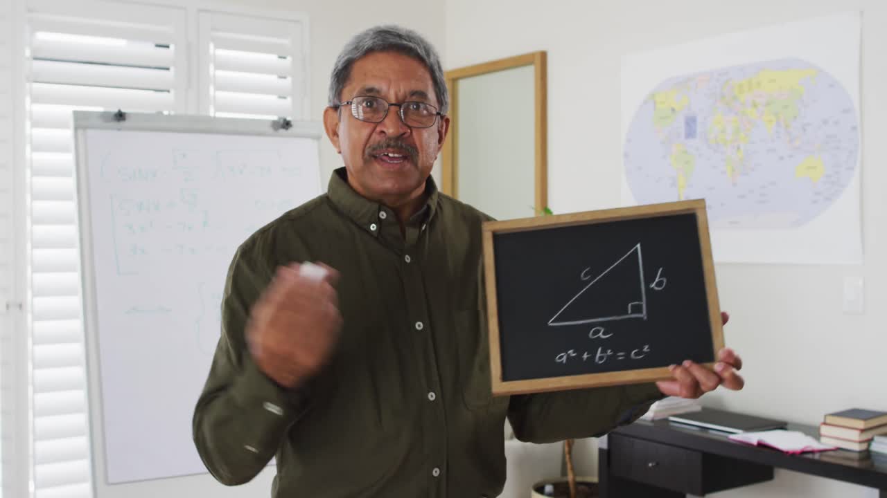 maestro de raza mixta de pie en una pizarra dando una lección en línea a la cámara