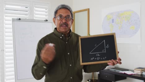 maestro de raza mixta de pie en una pizarra dando una lección en línea a la cámara