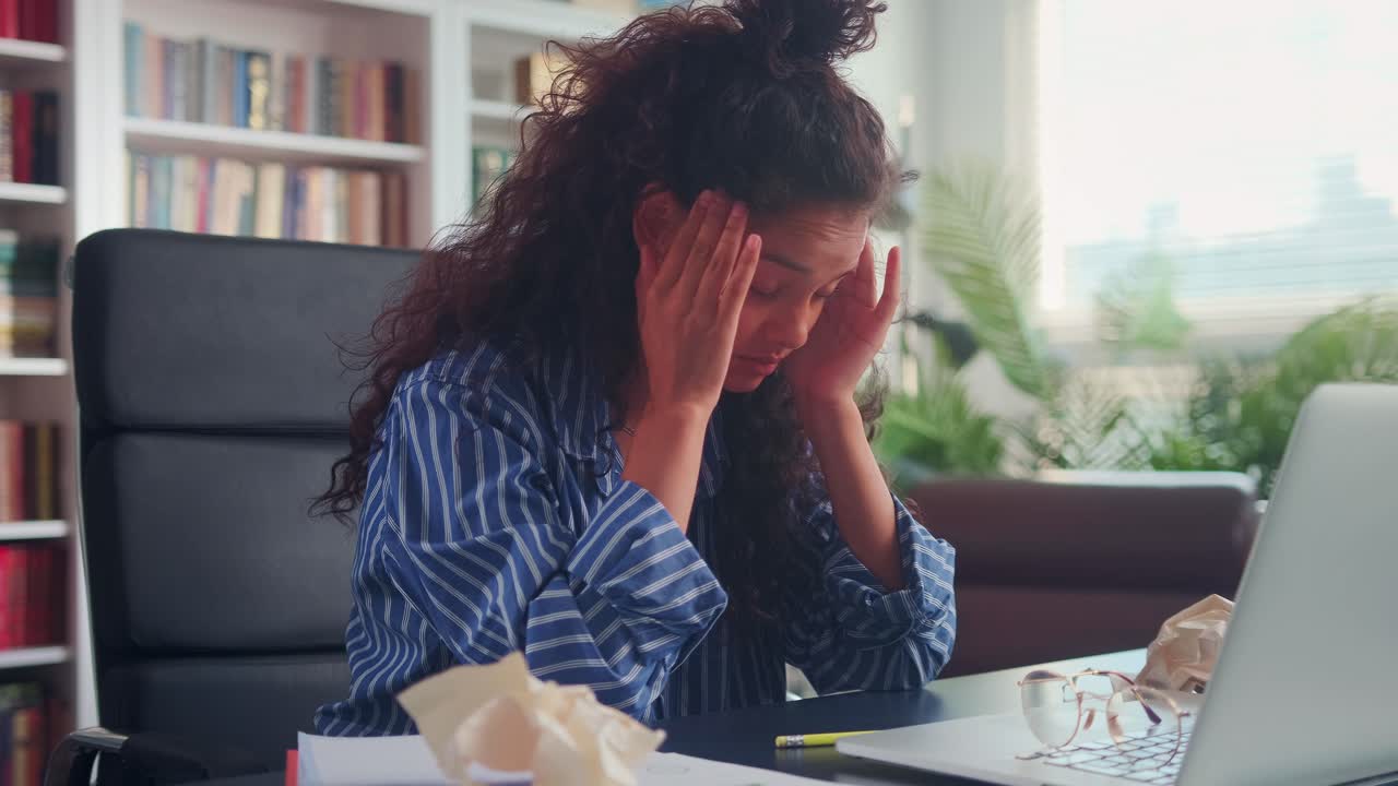 Tired indian young woman feels headache working with laptop in the office