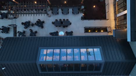 top-down view of a cafe terrace with black tables and chairs, string lights, and an awning