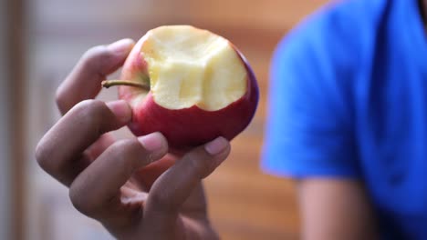 close-up of a person holding and eating a red apple