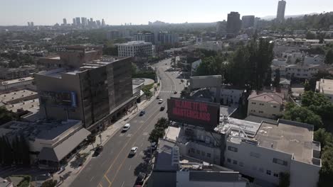 a stretch of sunset boulevard captured from above on a sunny day, as cars drive along the street as it curves in hollywood