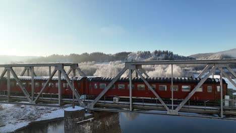 Toma-Aérea-De-Un-Paisaje-Noruego-Brumoso-Y-Soleado-En-Capas-Con-Un-Puente-De-Tren