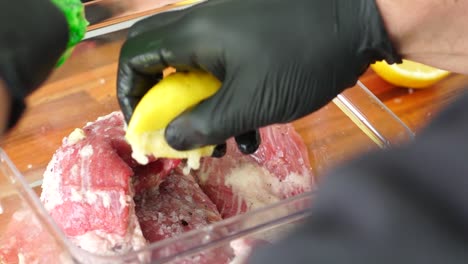 squeezing lemon seasoning raw meat for argentine bondiola, slow-motion close-up