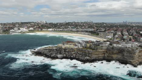 costa rocosa con horizonte de sidney y playa de bondi bay y olas tormentosas rompiendo en un acantilado en australia