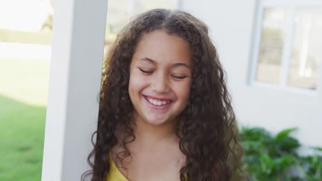 Video-of-happy-smiling-biracial-girl-outside-of-house