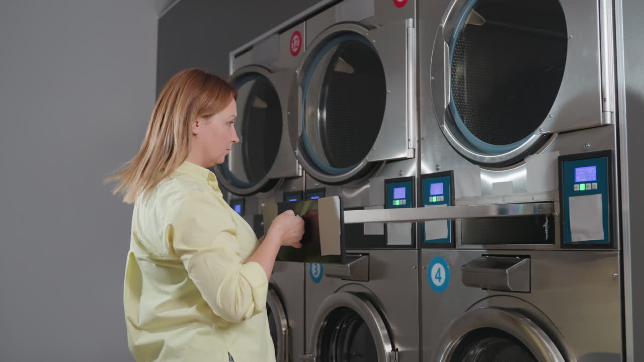Laundry worker pushes industrial washer filter drawer into compartment, locks with key after cleaning, performing routine maintenance in laundromat, professional service with safety procedure ensured