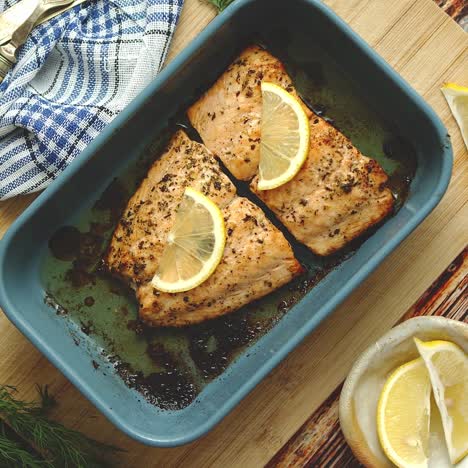 roasted salmon in heat proof dish  with aromatic dill  lemon  salt and pepper on sides