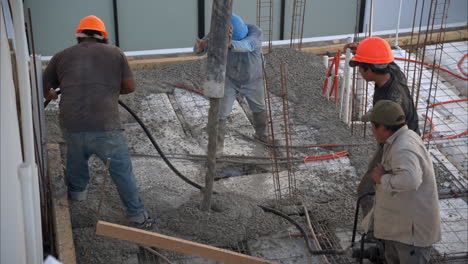 Cámara-Lenta-De-Un-Grupo-De-Trabajadores-De-La-Construcción-Latinos-Mexicanos-Vertiendo-Concreto-Fresco-Con-Una-Bomba-De-Pluma-Para-Crear-La-Losa-De-Una-Casa-En-México