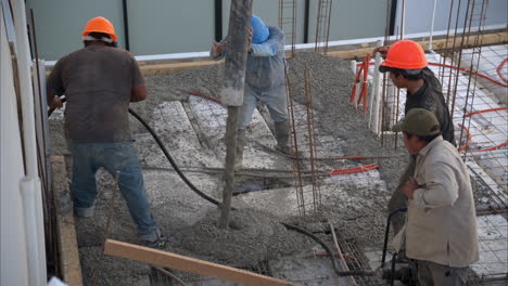 movimiento lento de un grupo de trabajadores de la construcción latinos mexicanos vertiendo hormigón fresco con una bomba de boom para crear la losa de una casa en méxico