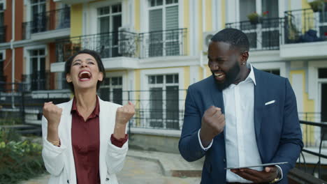 Business-couple-celebrating-outdoors.-Mixed-race-people-getting-good-news