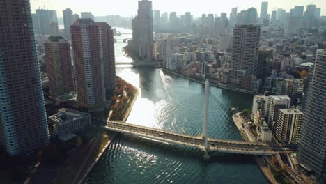 aerial drone flying over river between high rise buildings in tokyo city japan