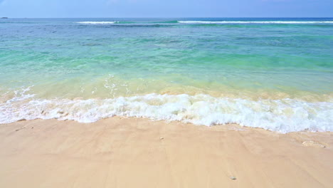 turquoise tropical sea waves breaking on sandy beach, slow motion full frame