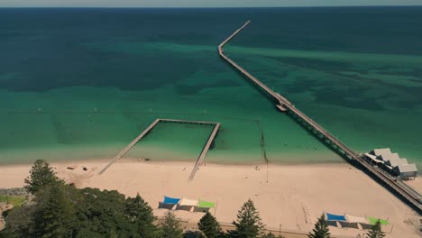 Aerial-View-Of-Busselton-Jetty-In-Australia,-Shoreline-Boardwalk-From-Beach-Into-Sea