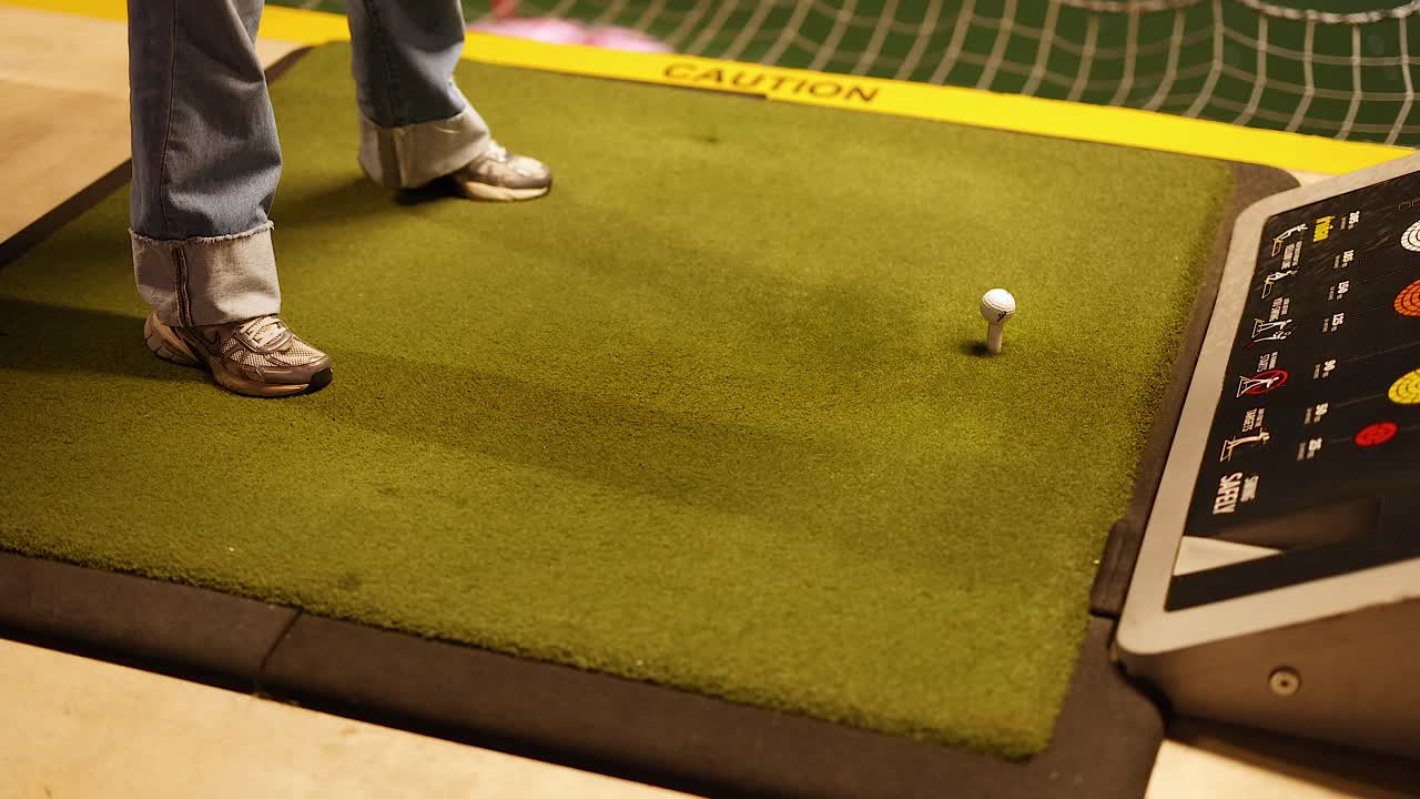 Donna che si esercita a giocare a golf in un campo da golf interno