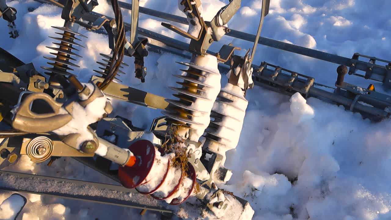 Detailed view of abandoned high voltage railway catenary insulators resting in deep snow, illuminated by warm sunlight with crisp shadows and visible ice textures
