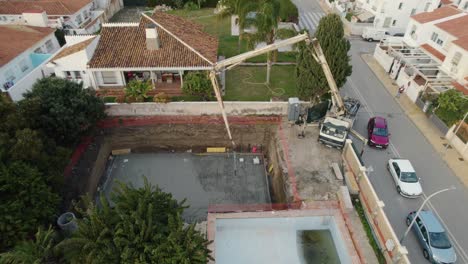 Construction-site-in-a-residential-area,-crane-and-man-working-on-the-cement