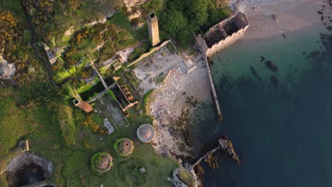 porth wen abandoned coastal derelict brickworks remains golden sunrise countryside bay aerial view slow spiral birdseye