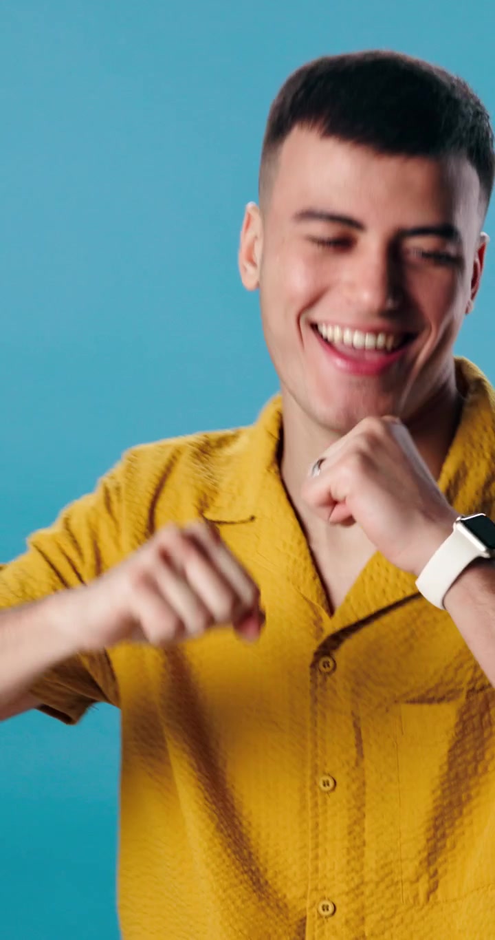 Giovane uomo felice che balla e sorride su sfondo blu