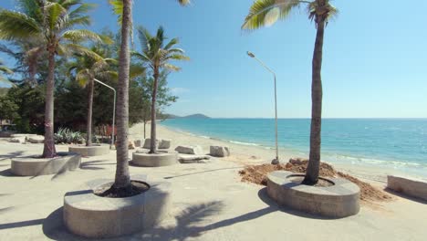 aerial: dolly in fly towards palm trees and flying closely between them revealing a tropical shoreline and the ocean, south-east asia, thailand