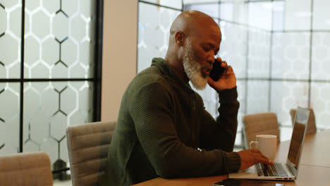 Businessman-talking-on-mobile-phone-while-using-laptop-4k