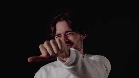 trendy young man unsure thumb up and down gesture, close, black background