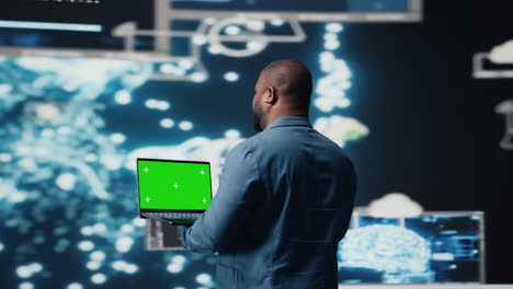 black engineer works on binary code with chroma key on laptop