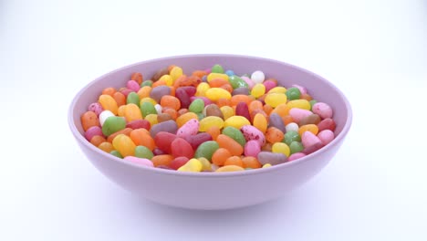 pile of small bean shaped sugar jelly candies. rotating in purple bowl on the turn table. isolated.