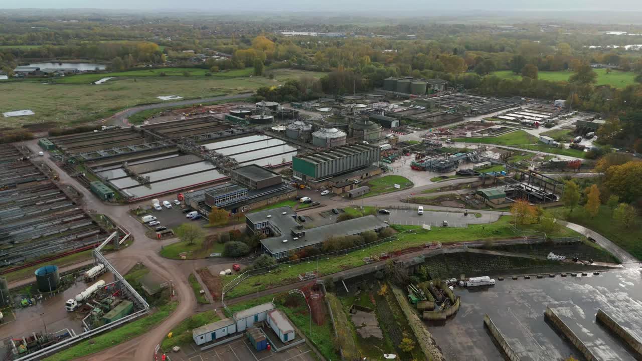 Cinematisk dronevideo af Severn Trent-spildevandsanlæg med sedimentationsbassiner, tanke, cirkulære klaringsanlæg og industriel layout nær Leicester, England