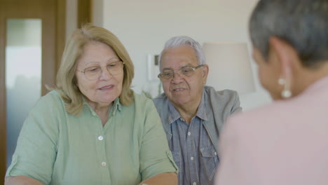 senior couple sitting at table, talking with realtor and discussing details of agreement