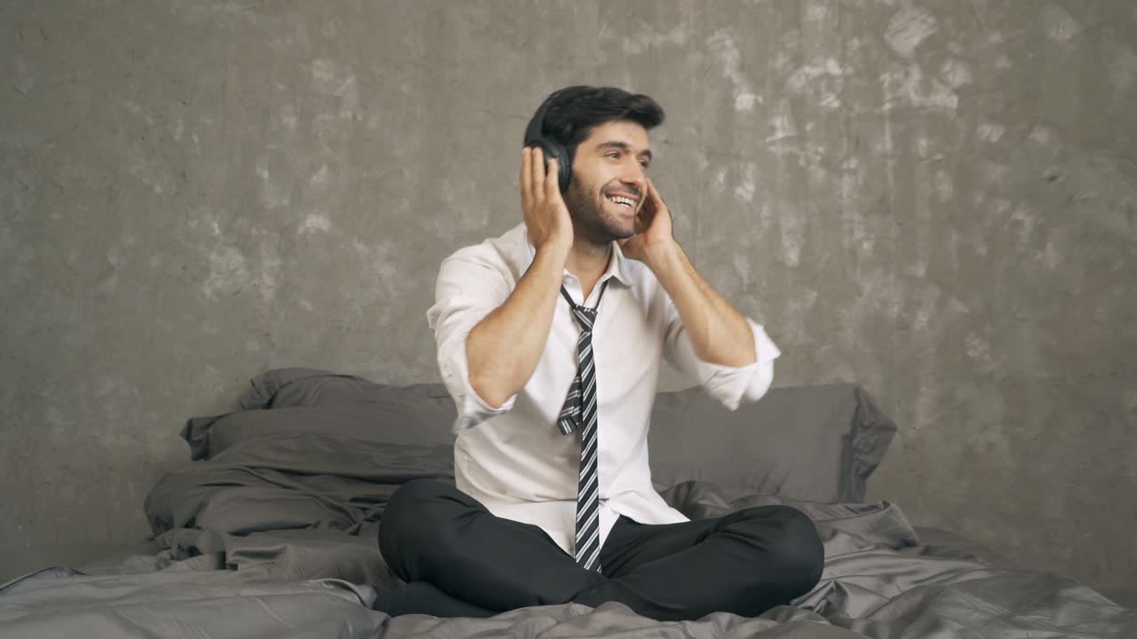 retrato de relajarse empresario de oriente medio, ceo con auriculares bailando en la cama, escuchar música en el dormitorio con teléfono inteligente móvil. entretenimiento ocio divertido. estilo de vida de la gente en casa.