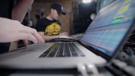 sound producer is using digital audio workstation on a laptop, sitting in a room of recording studio