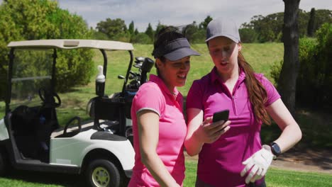 Dos-Mujeres-Caucásicas-Jugando-Golf-Usando-Un-Teléfono-Inteligente