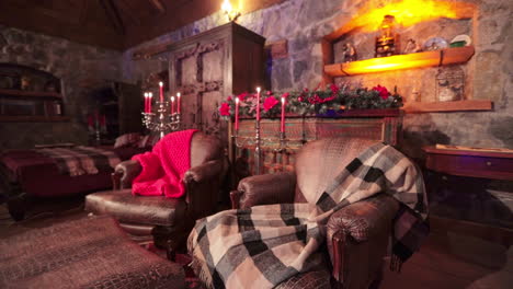 old-fashioned living room in the stylish country house. big leather armchairs with warm plaids, wooden furniture, candles and christmas decorations.