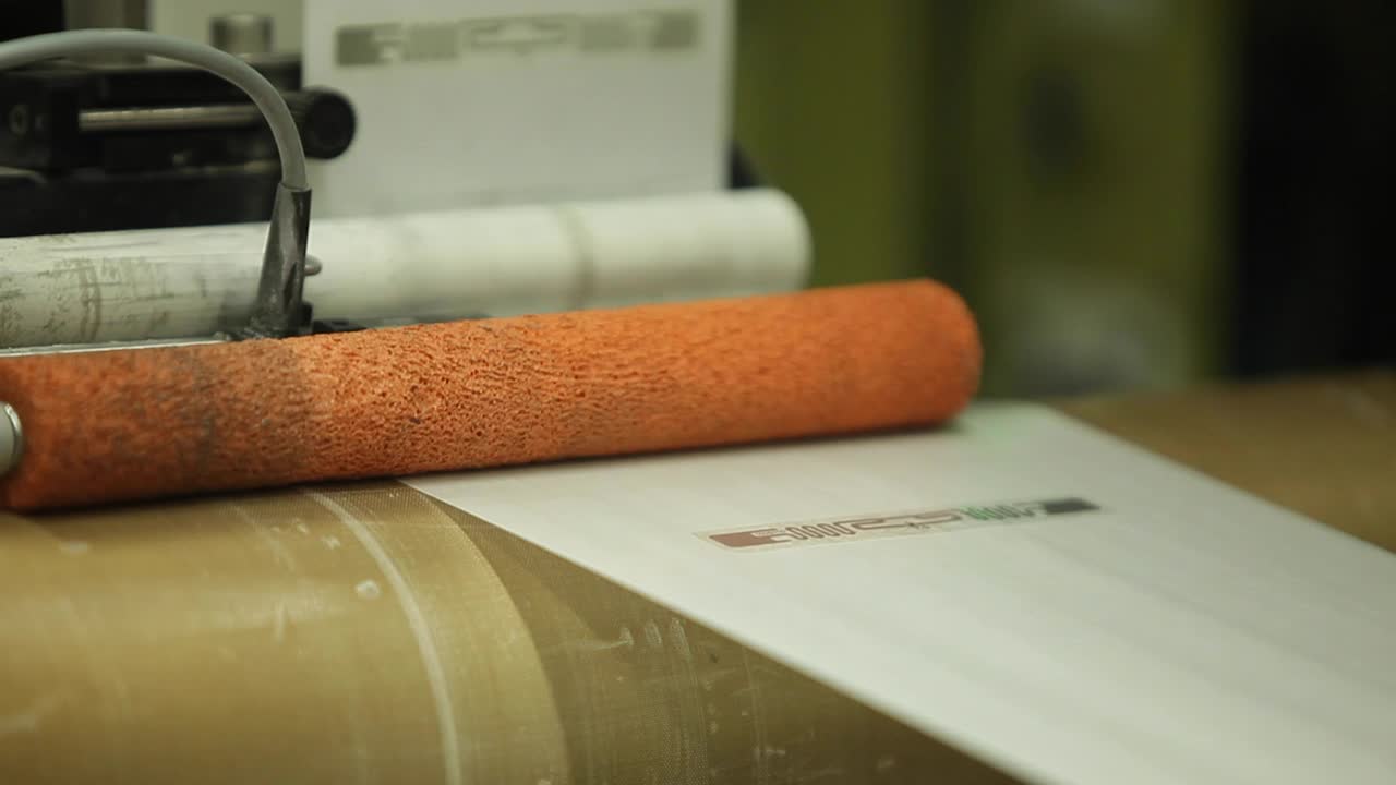 Orange Label Printing Rolls with High speed labeling machine in industrial factory, sticker on product in manufacture. Flexible packaging. Close-Up Macro.