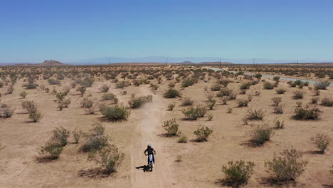 a lone male motorcyclist riding through the bright and peaceful mojave desert in california on a bright summer day - aerial shot