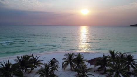 lovers kiss and hug on the sunset sok san beach at sunset, with palm trees, white sand and calm turquoise water in koh rong island, cambodia. perfect aerial view flight panorama overview drone