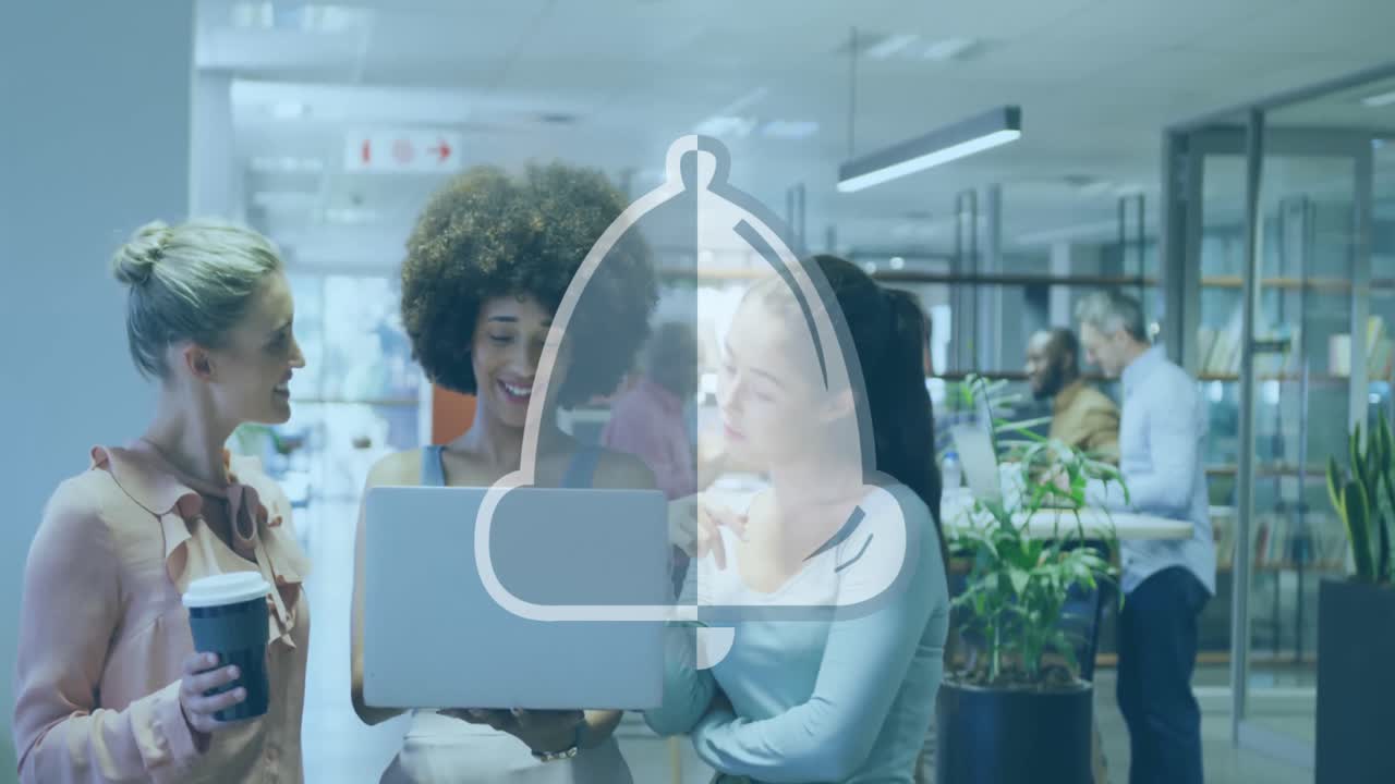 Animation of bell icon over diverse female colleagues discussing over a laptop at office