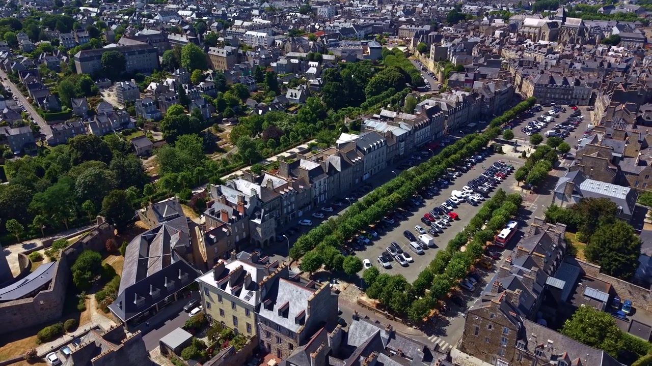 Sorvolo con drone del Castello di Dinan e di Place Duguesclin, rivelando la piazza alberata, la città medievale e il centro storico in estate.