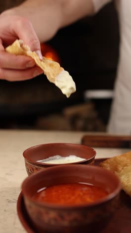 hand dipping flatbread into sauces