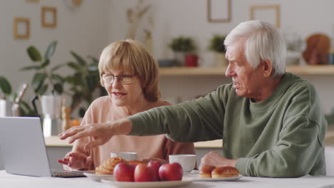 Senior-Couple-Using-Laptop,-Chatting-and-Embracing-at-Home